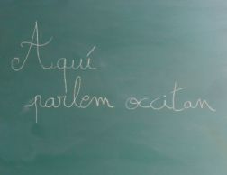 Un tablèu amb escrich a la man « Aquí parlem occitan »